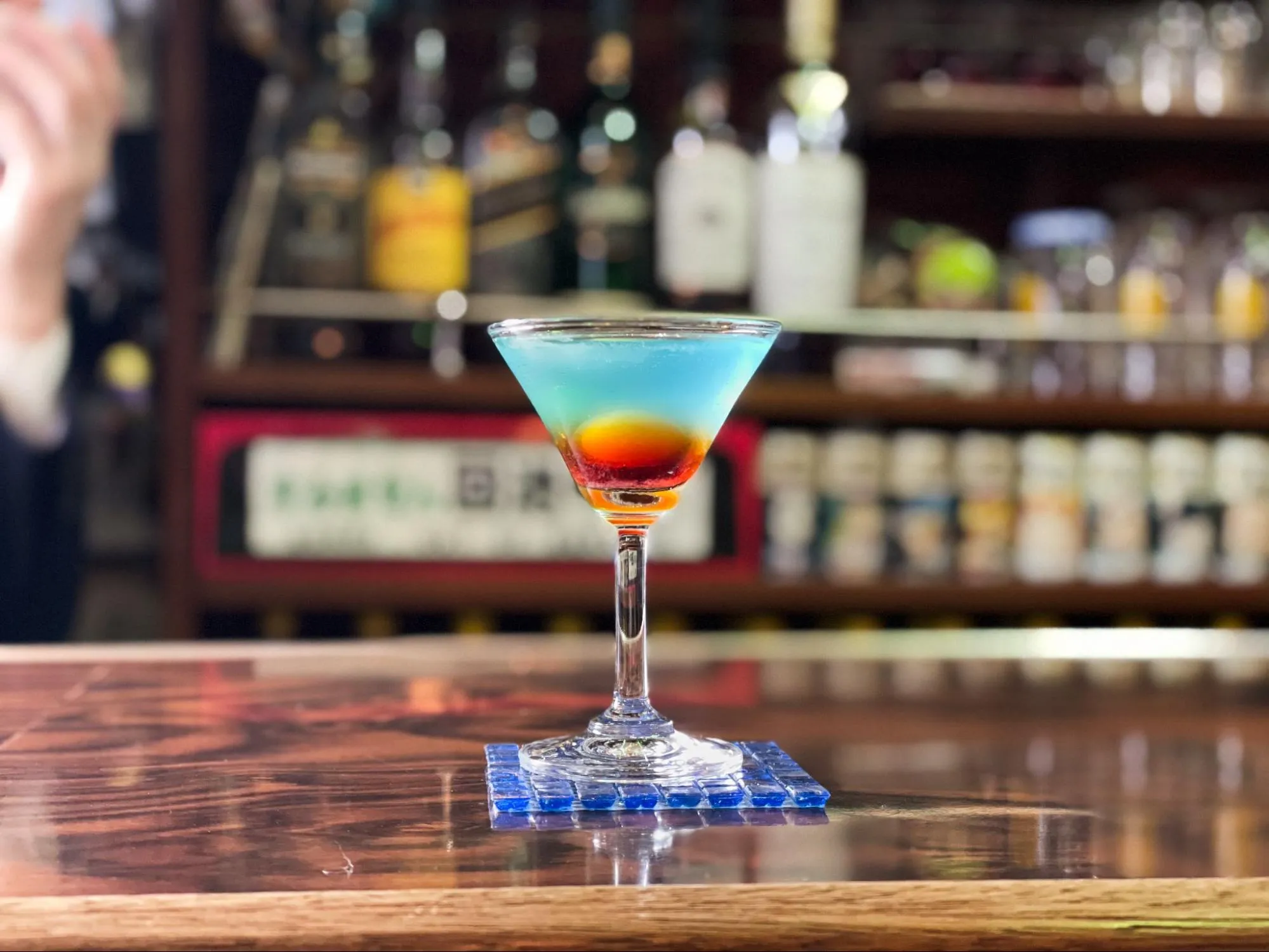 「洋酒喫茶 プリンス」の、ジンベースに赤いグレナデンシロップで“日の出”、ブルーキュラソーで“海”を表したカクテル「みちのく潮風トレイル」。真ん中にある“太陽”は、生のうずらの卵。