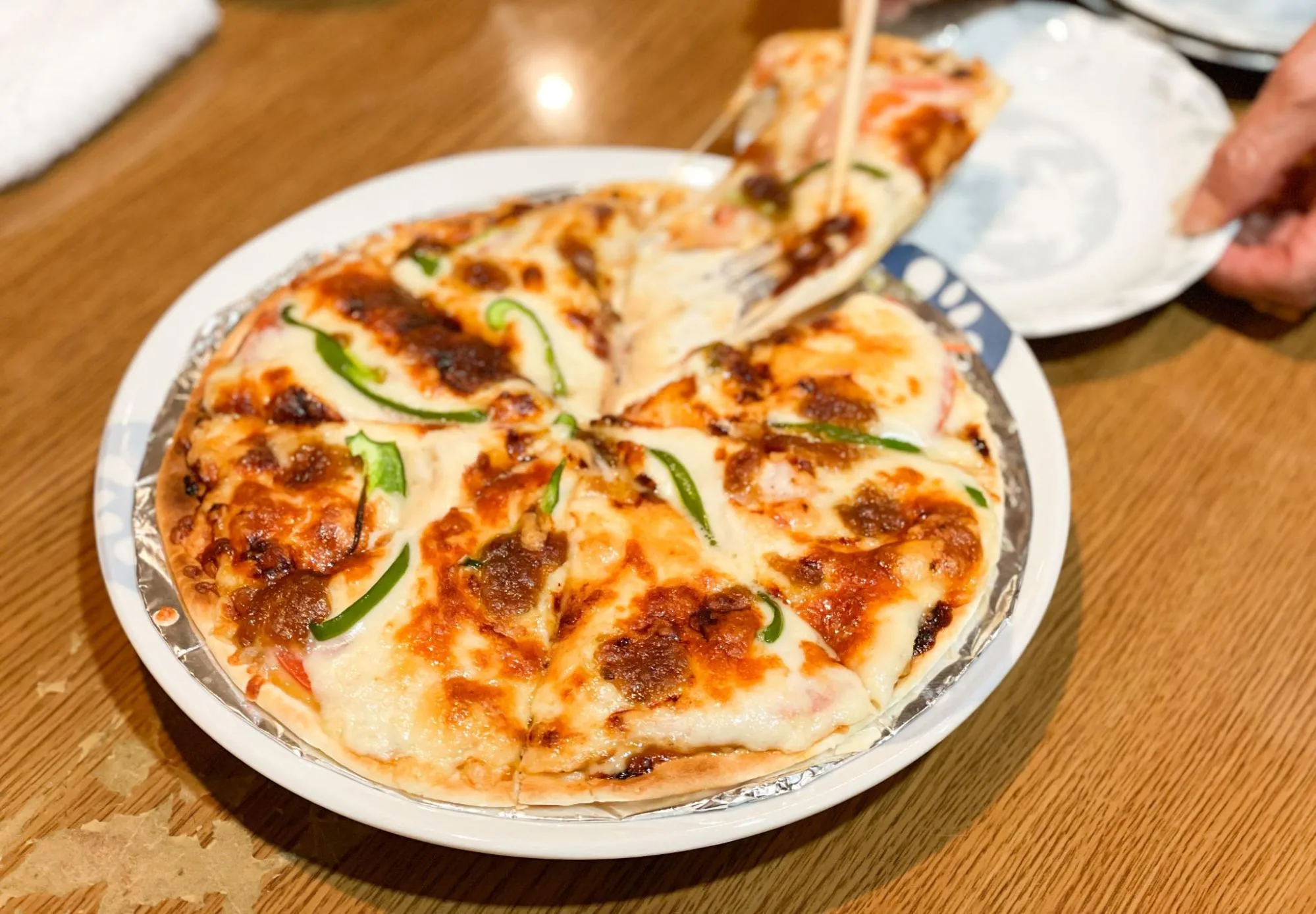 「おかげさん」の、薄い記事に青なんばんソースとチーズがたっぷりのった「自家製青なんばんソースピザ」